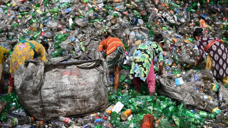Workers sorting plastic waste at a landfill in Chattogram, Bangladesh. Environmental and recycling theme. — PET Recycling Off