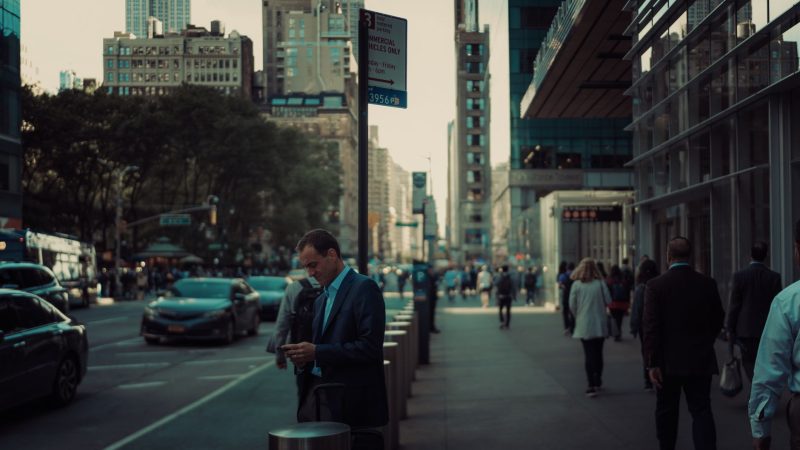 Street view in New York City with pedestrians and skyscrapers, capturing the urban hustle. — Understanding Forex Market Dynam